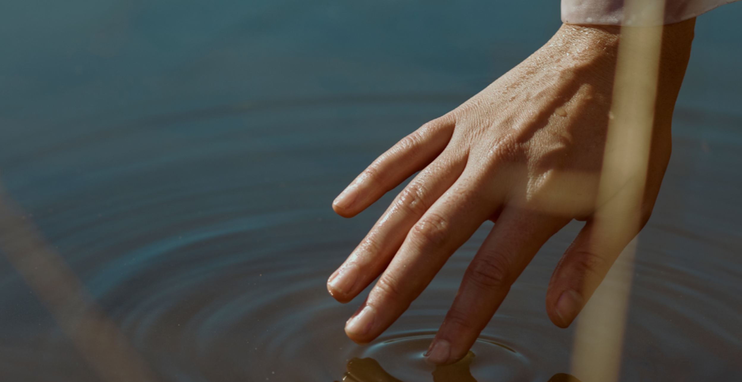 a hand gesturing gently on still water